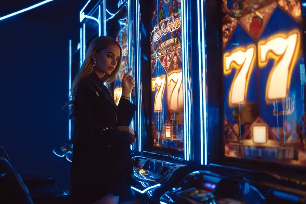 Uma mulher sorrindo perto de máquinas caça-níqueis brilhantes com símbolos de sorte, mostrando as emocionantes opções de slots do 67VIP.